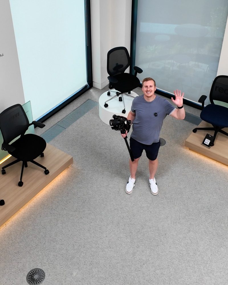Sam waving at the camera from an office shoot