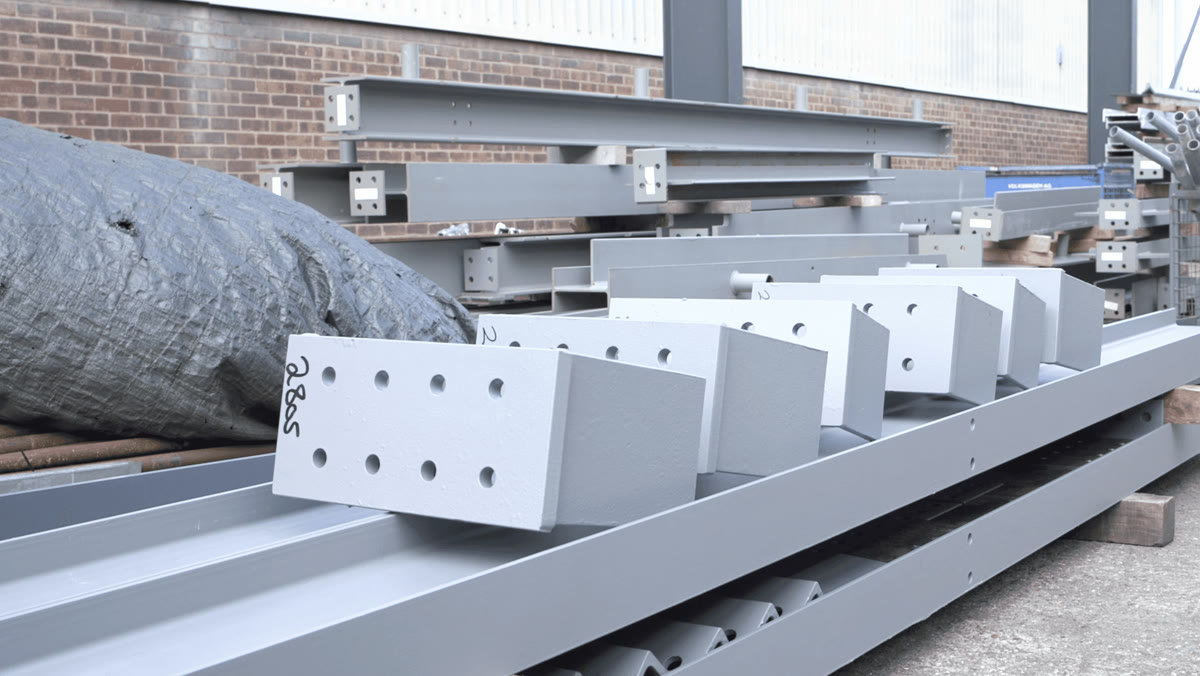 Primer-coated fabricated steel beams and column sections with drilled connection plates in the Apex yard