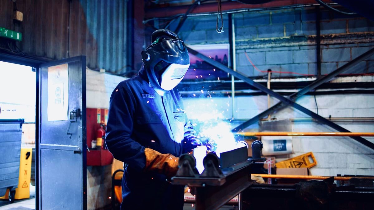 An Apex Steel Structures welder fabricating a steel section, sparks flying