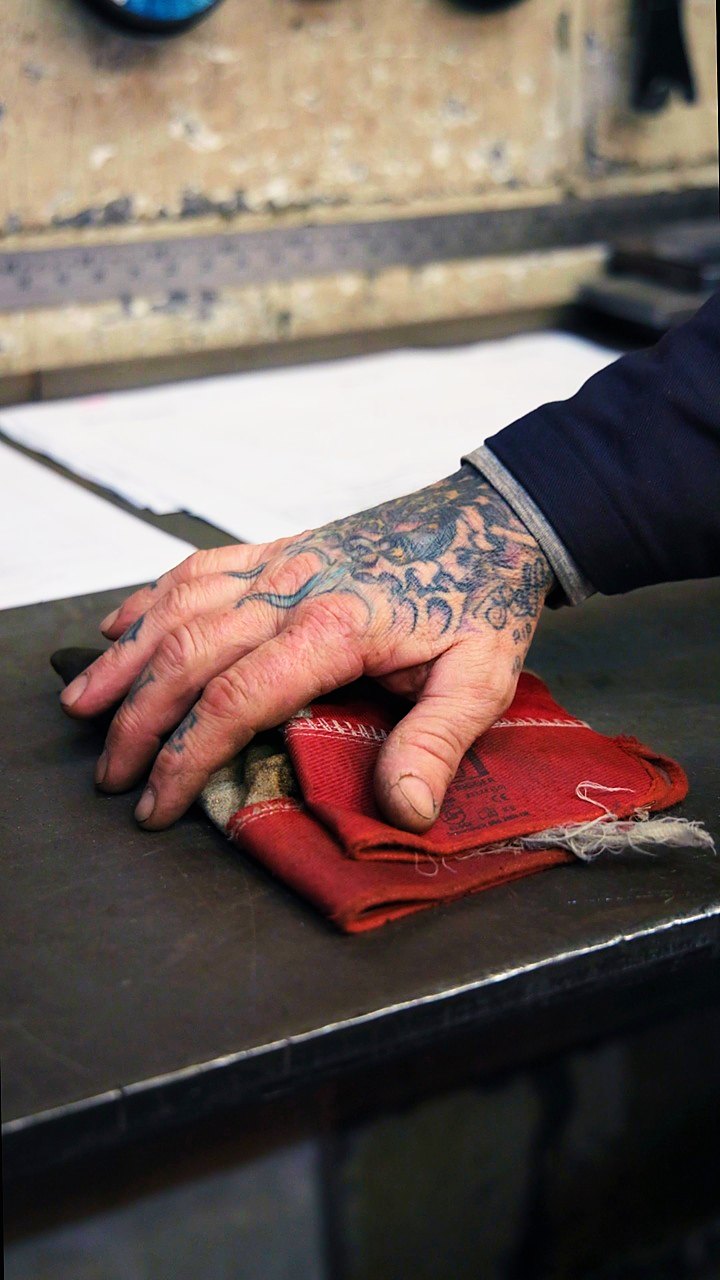 A fabricator's hand resting on a red cloth on the Apex workshop bench