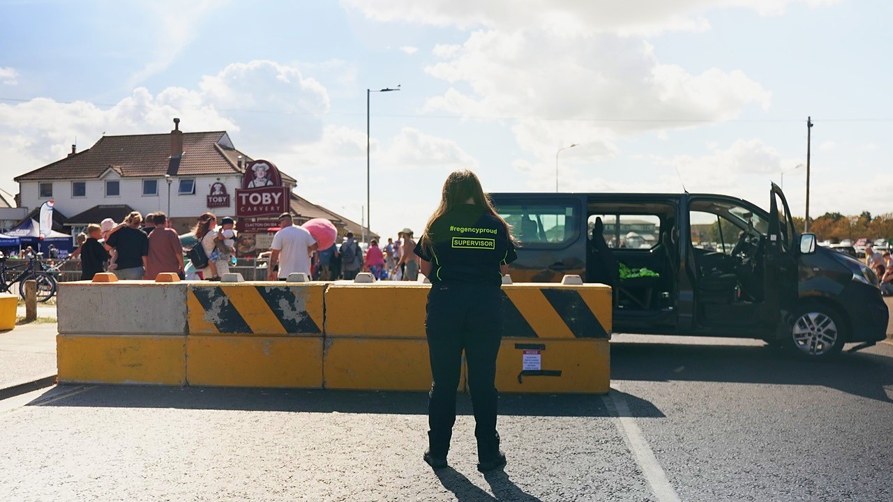 A Regency Security supervisor at a road closure with crowds behind, at Clacton Airshow