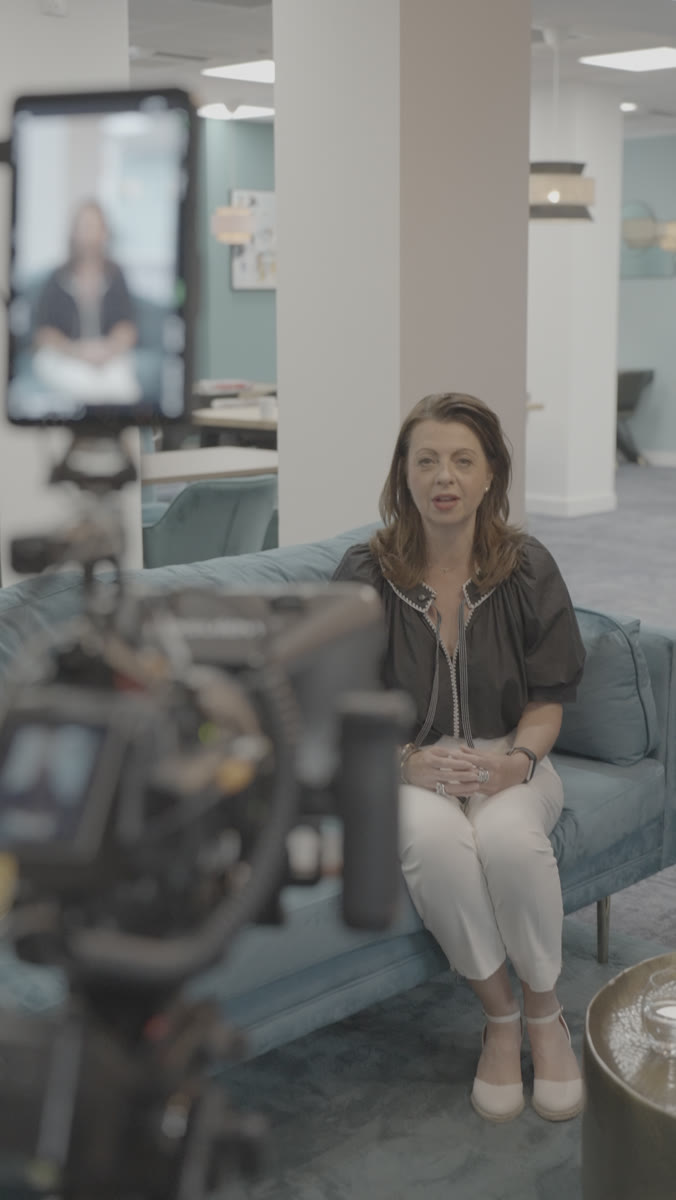 Liz Flavell being filmed on a sofa in a styled boardroom set