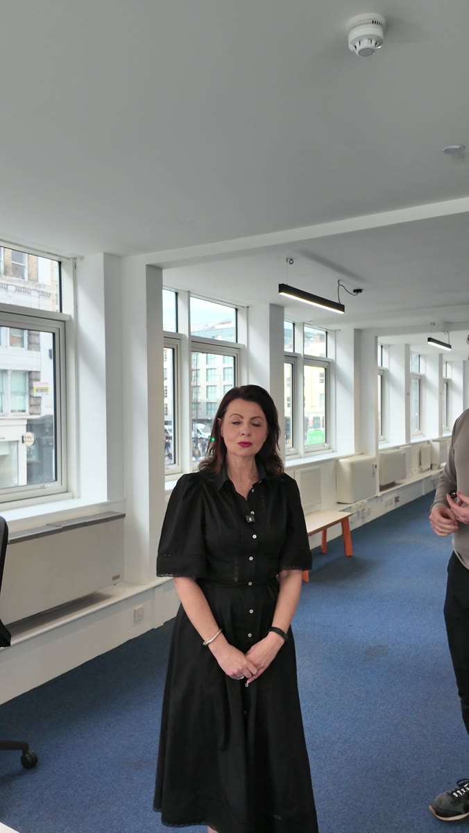 Liz Flavell delivering to camera on location in a City office