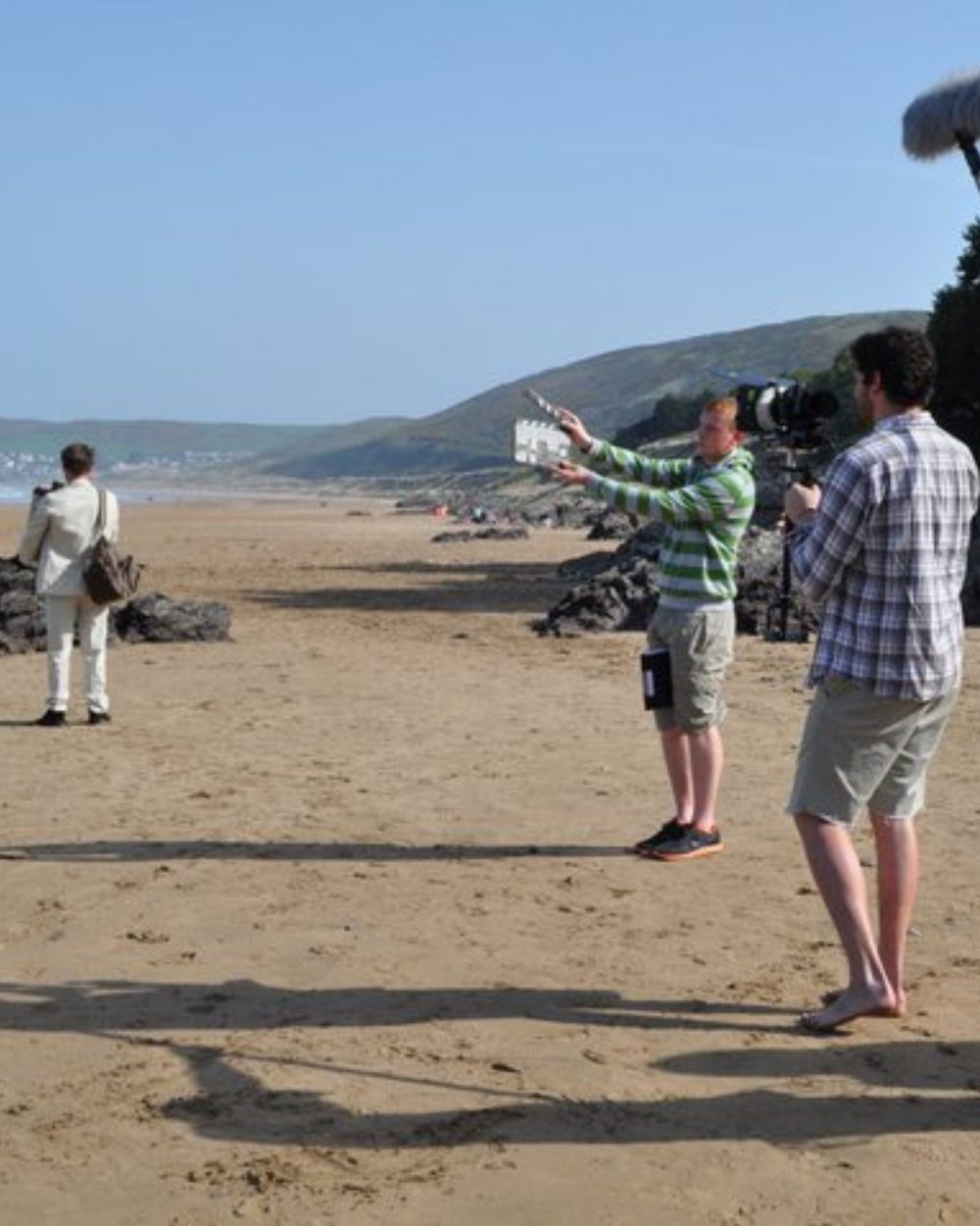 Sam and a crew filming on a beach during film school
