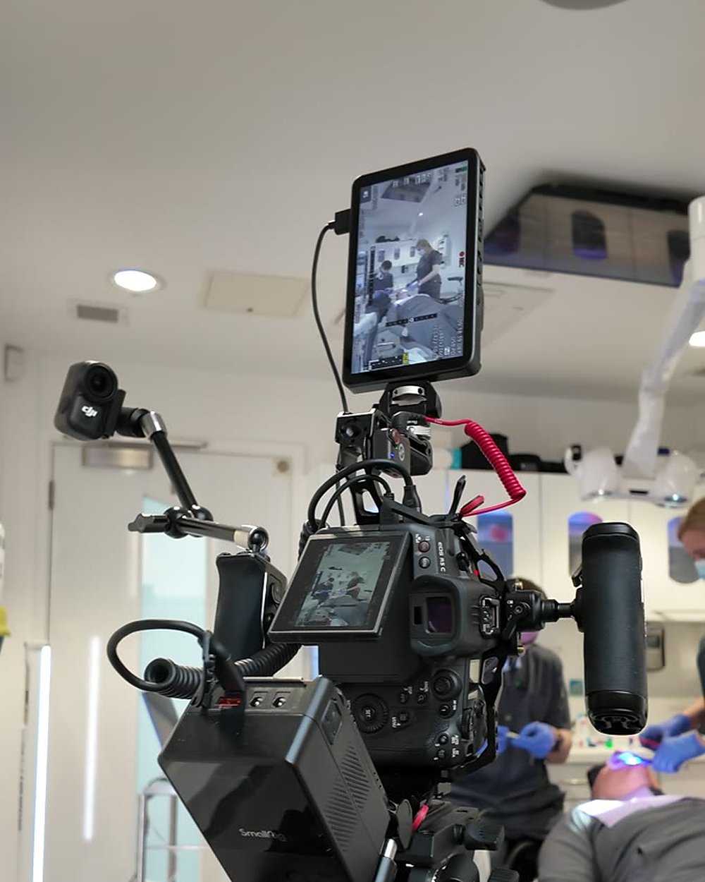 Our camera rig on a tripod in a dental surgery, with a dentist treating a patient behind it