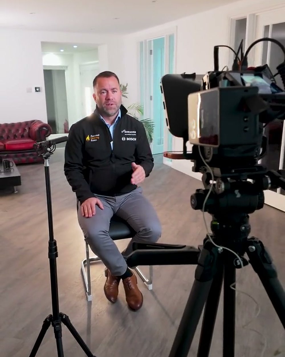 An expert seated for an interview with a camera and teleprompter on a tripod in the foreground, the start of a video to blog post