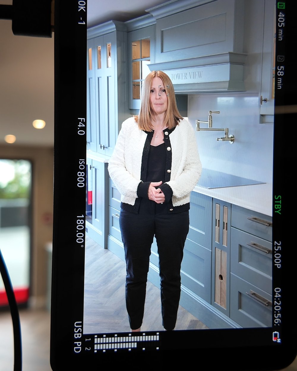 Camera monitor showing a presenter framed in a kitchen showroom, the video that sits at the top of the page