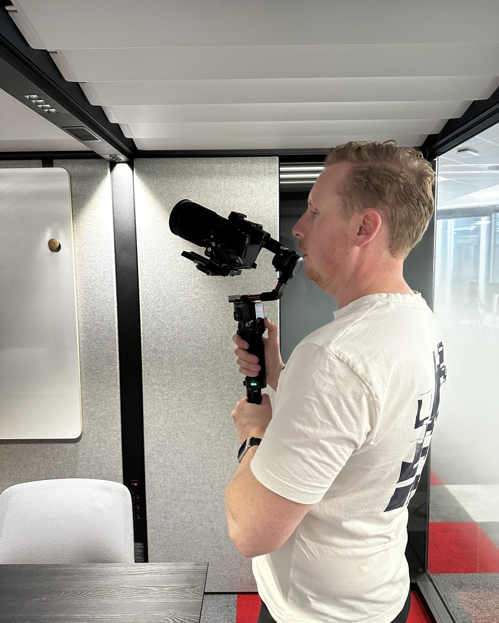 Sam in profile holding a gimbal-mounted camera with a shotgun mic