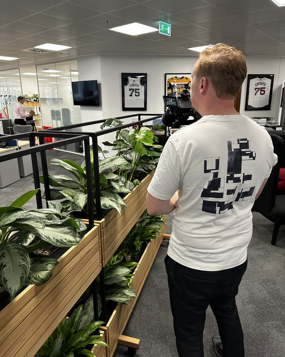 Sam walking a gimbal camera along an office plant divider to capture a moving shot