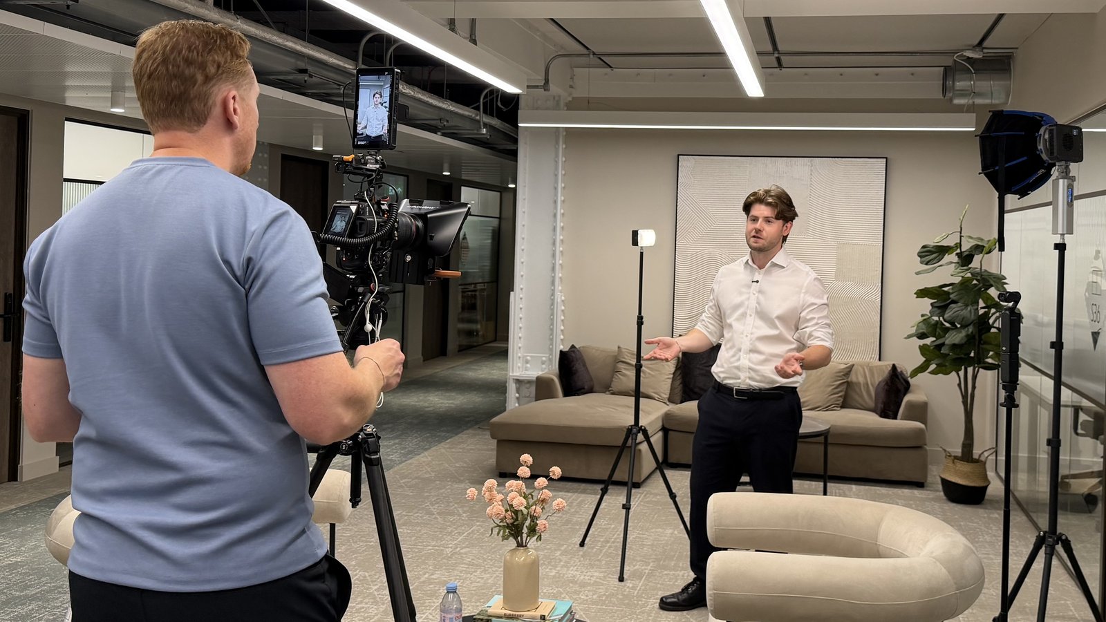 Sam at the camera framing an interviewee in a lit lounge set