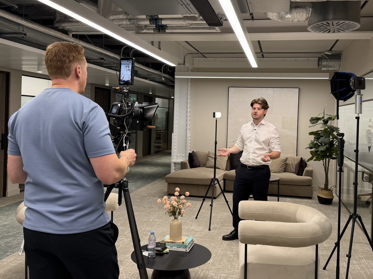 Sam at the camera framing an interviewee in a lit lounge set