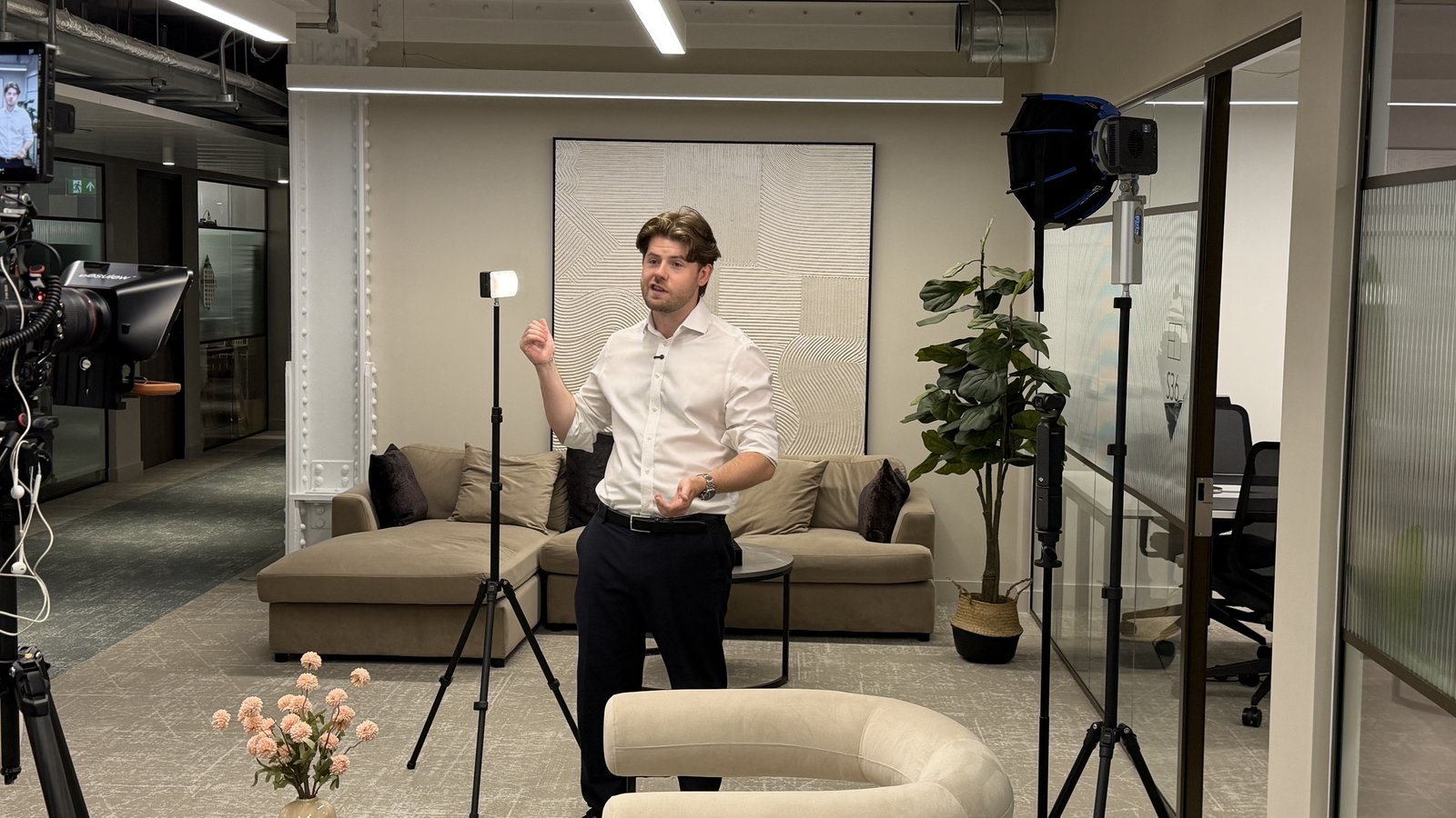 An interviewee talking to camera in a lit lounge set with light stands either side