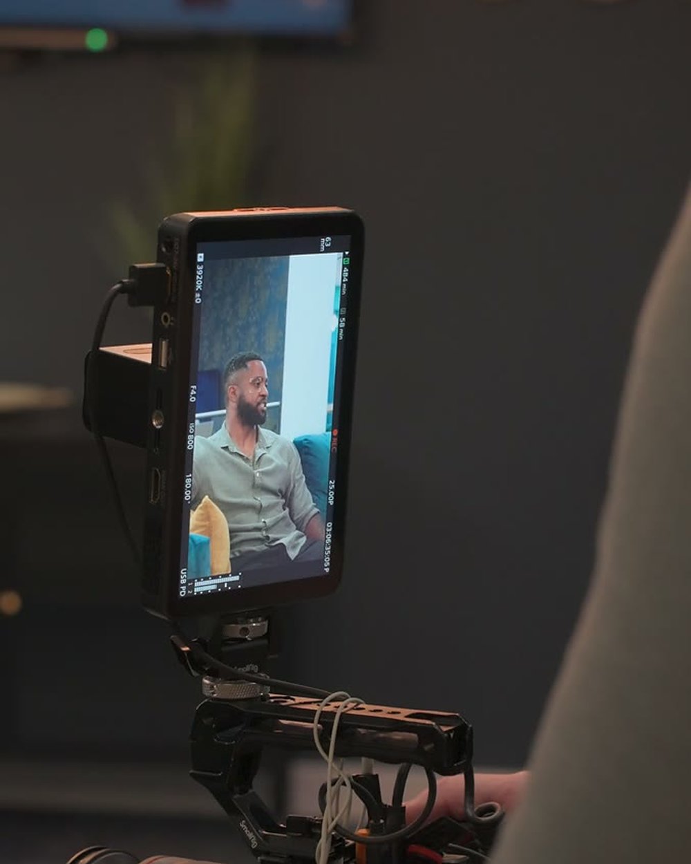 A camera monitor on our rig showing an interviewee framed on a sofa during a shoot