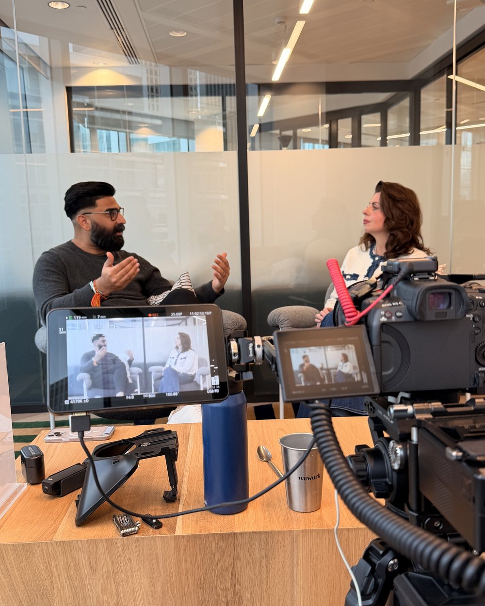 Two camera interview setup with a monitor showing 2 people across a coffee table