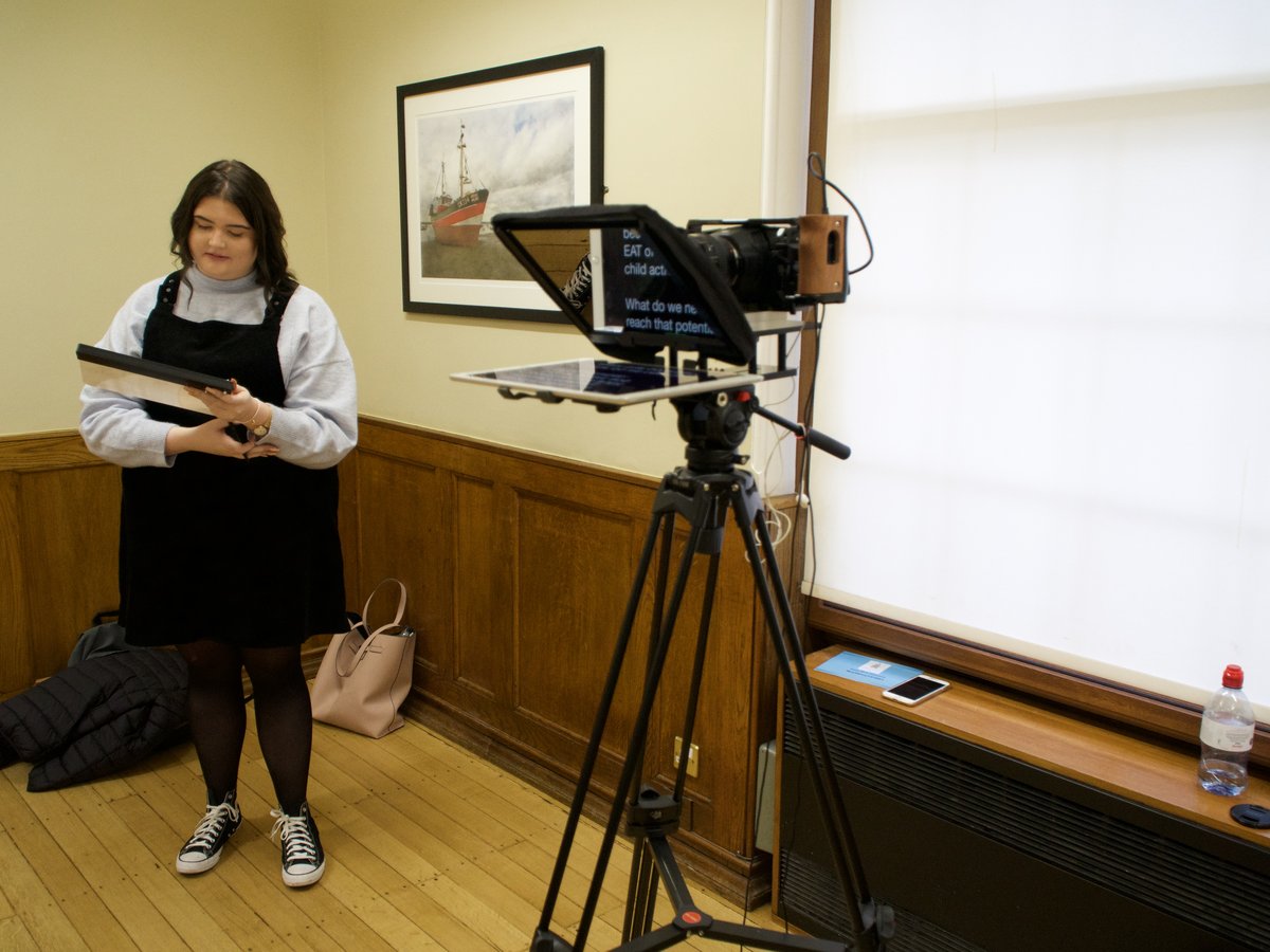A presenter reads through her script beside a teleprompter rig before a shoot