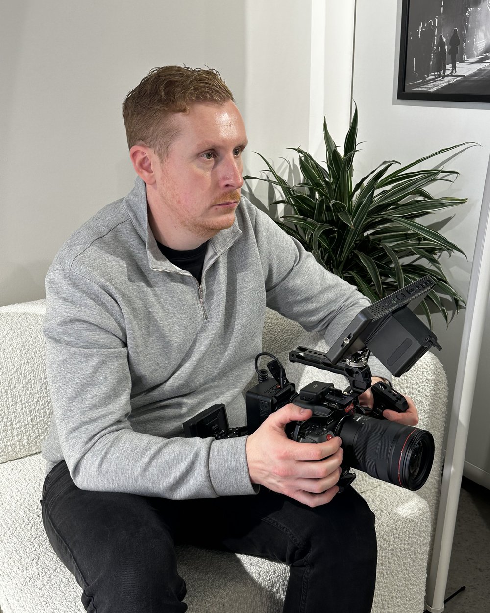 Sam seated on a sofa checking the monitor on his cinema camera