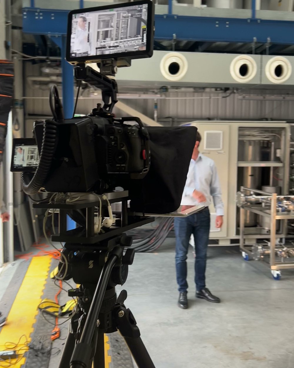 Cinema camera and monitor on a tripod in the PowerLoad factory with a softbox beside it