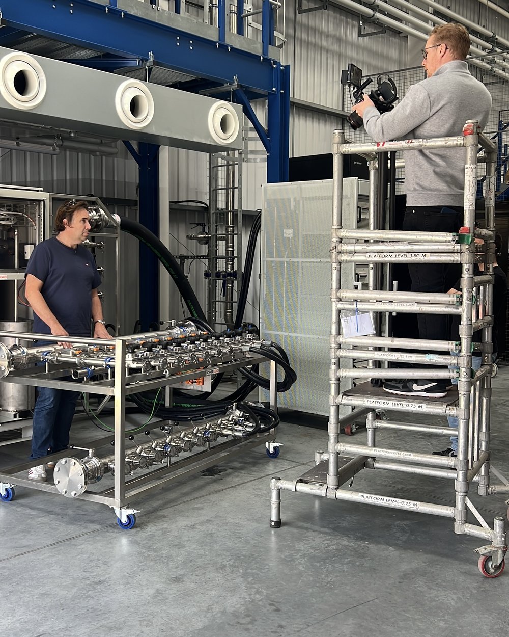Sam on a scaffold tower shooting a promo while the PowerLoad team works on the rack below