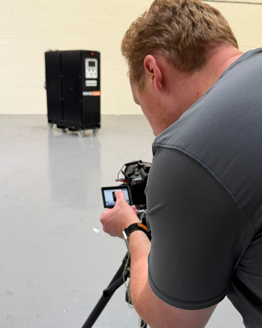 Sam checks the camera screen on a tripod with the finished product sharp in the background