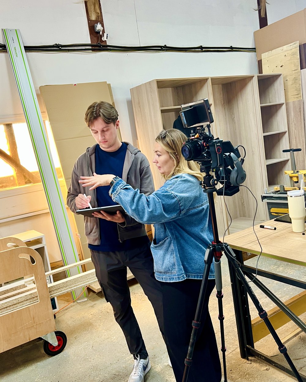 A producer shows the interviewee the script on a tablet beside the camera on a tripod